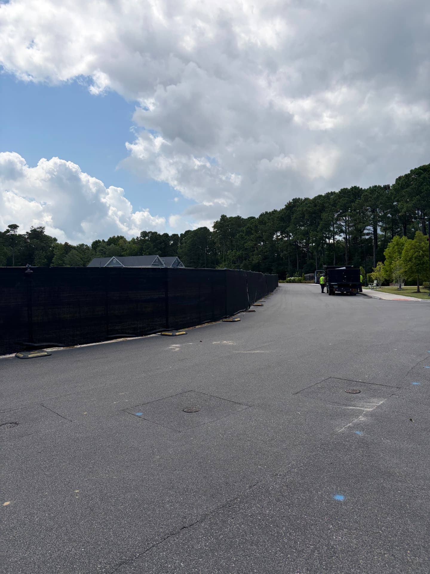 Long run of black windscreen fence along a paved road in a new development