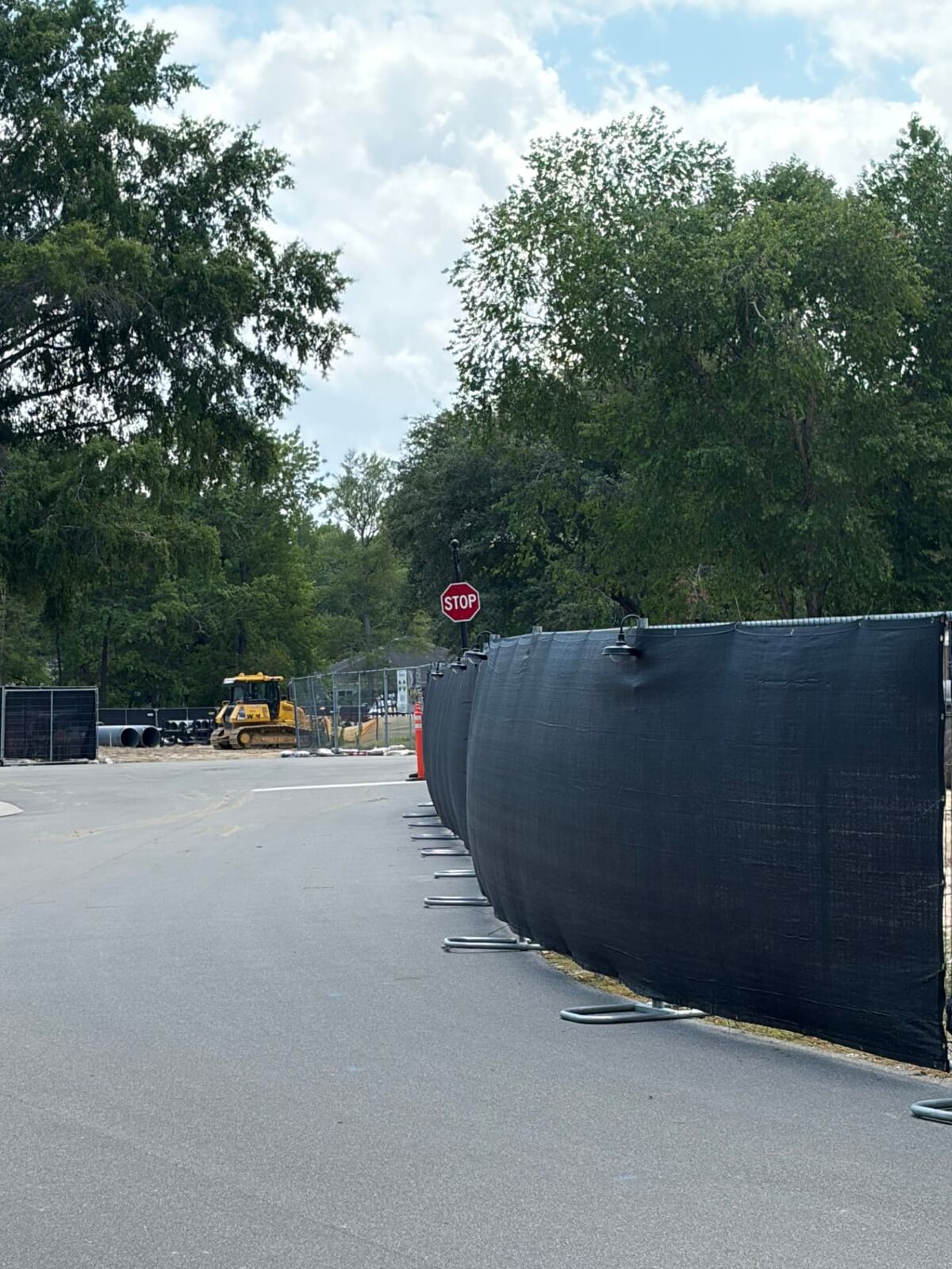 Black privacy windscreen fence along a curving road near a job site