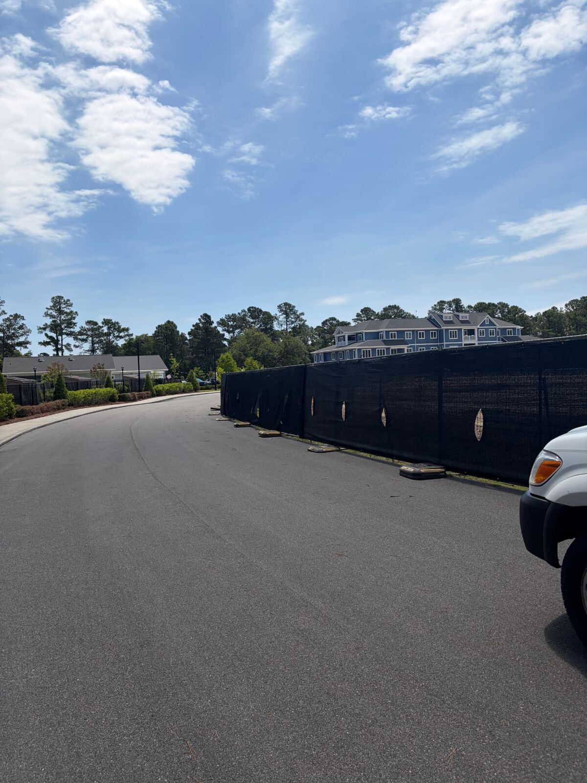 Temporary fence panels with black windscreen lining a paved road