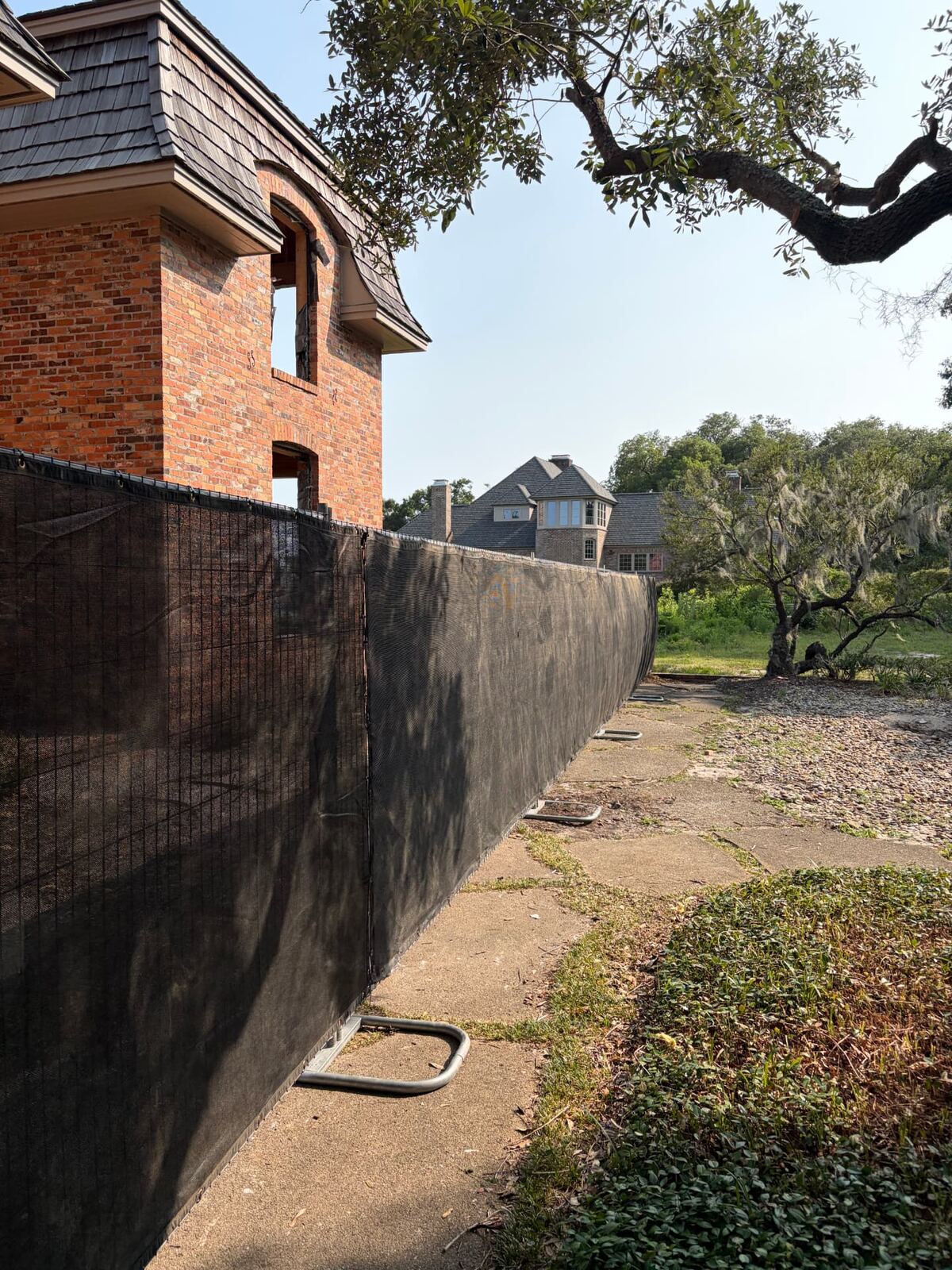 Privacy windscreen fence beside a brick home under construction