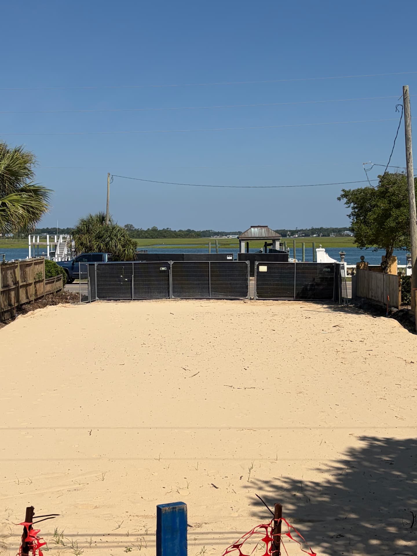 Temporary fence enclosing a sandy waterfront lot near the marsh