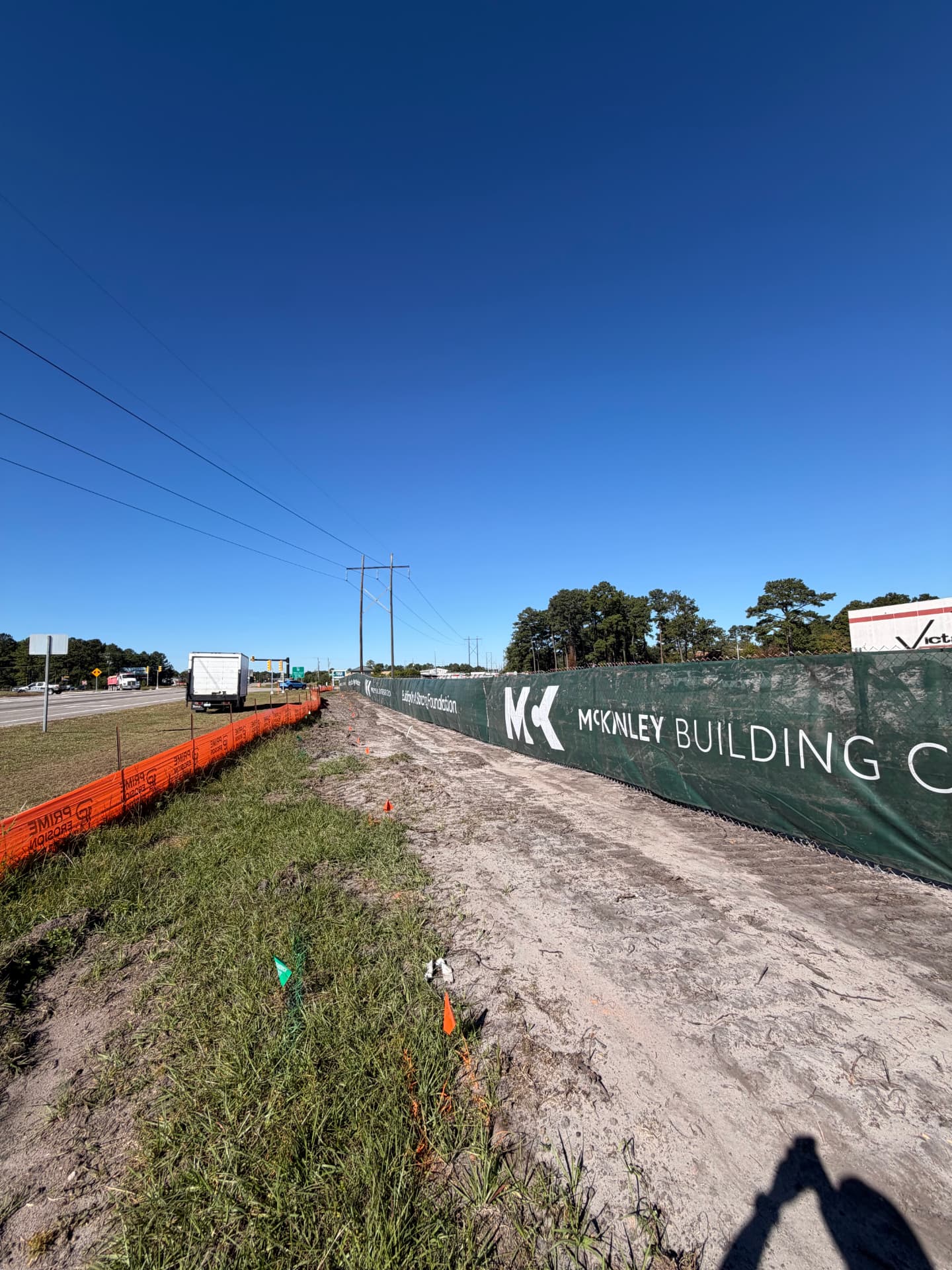 Custom printed contractor banner on temporary fence beside a highway