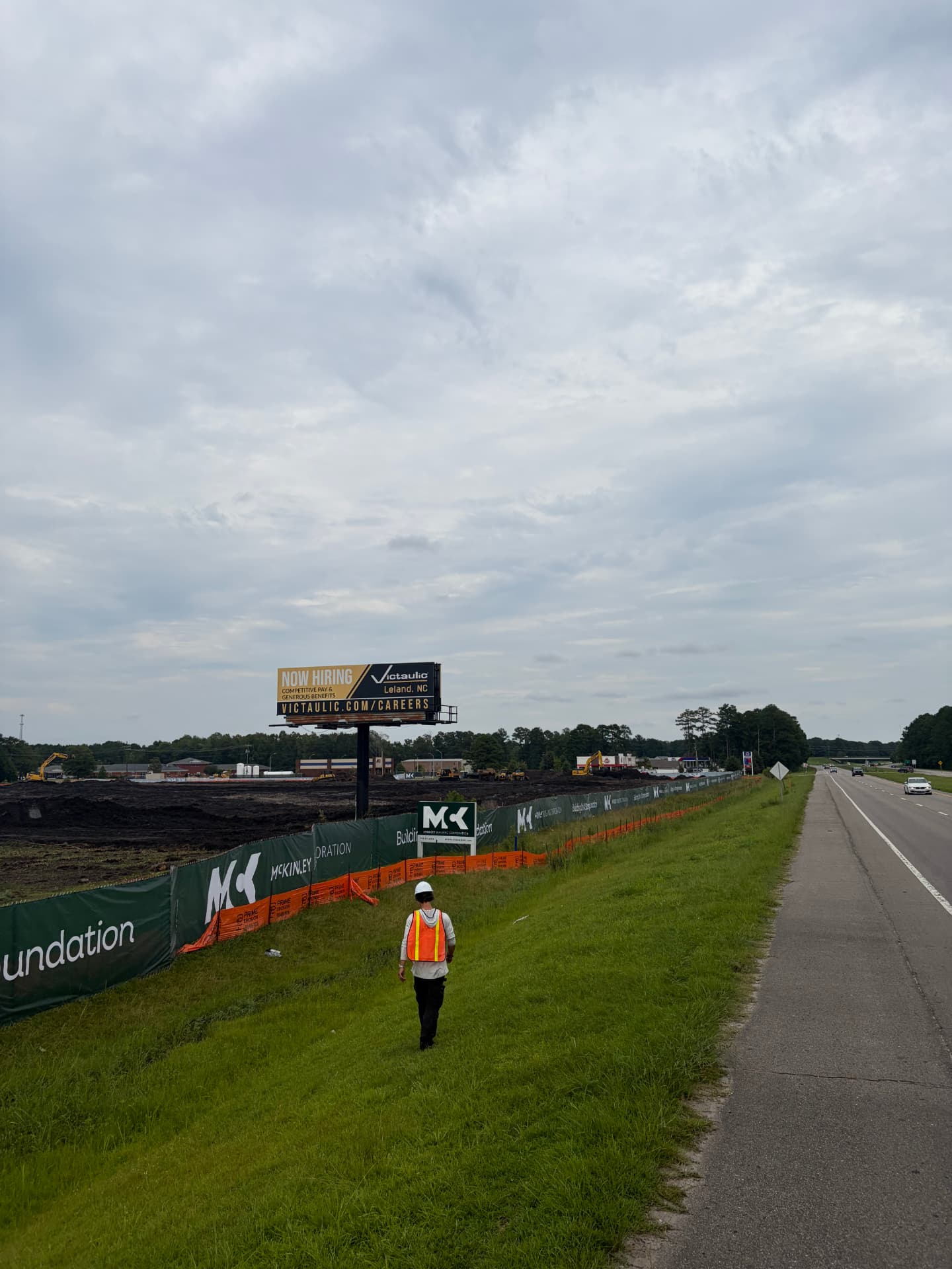 Branded windscreen banners on temporary fence along a highway job site