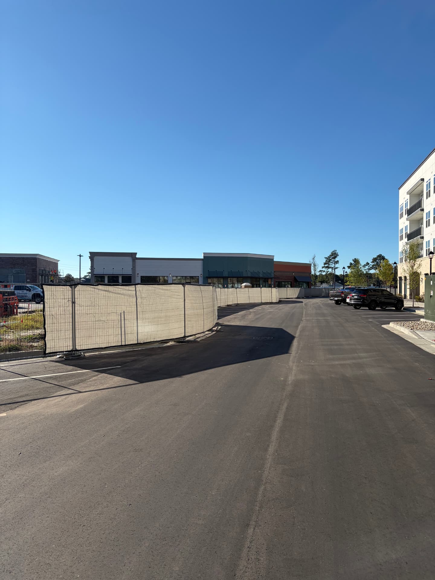 Screened temporary fence along a road beside a new retail center